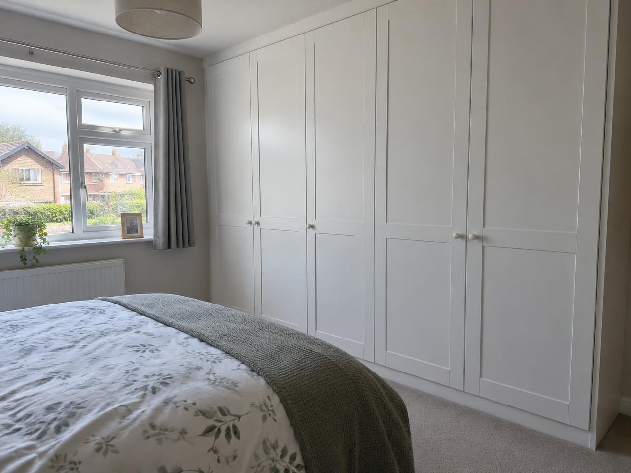 Illustrative white painted fitted wardrobes along a bedroom wall